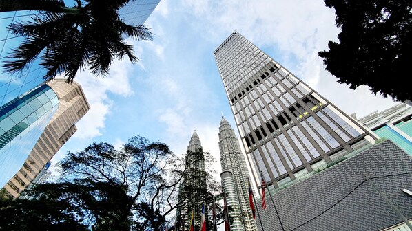 A view of the Petronas Twin Towers and surrounding modern buildings, including a curved glass structure. - Tropicana World The Residence KLCC (Kuala Lumpur)