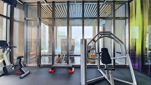 Een moderne sportschool met fitnessapparatuur, een zwembad en grote ramen met uitzicht over de stad.