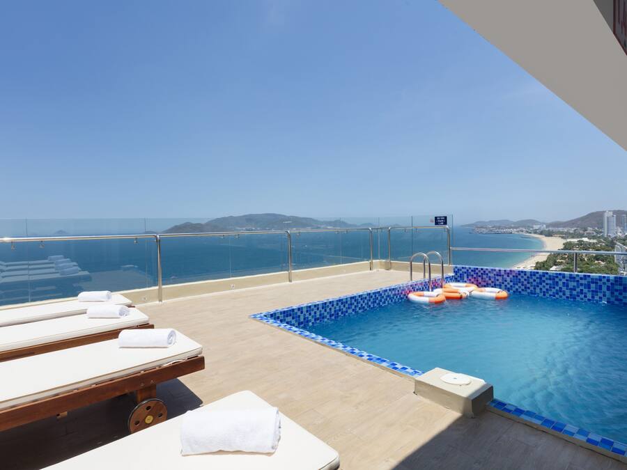 A rooftop infinity pool with lounge chairs and a view of the coastline.
