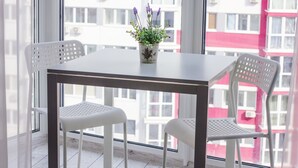 Un tavolino con due sedie bianche e un vaso con fiori viola.