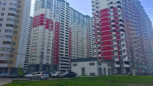 Un palazzo residenziale a più piani con diversi balconi e un'area di parcheggio antistante.