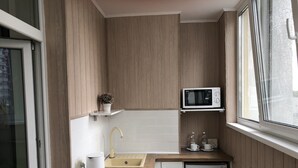 Una cucina compatta con mobili in legno, un forno a microonde, un lavandino e un piccolo frigorifero.