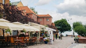 Un caffè all'aperto con tavoli e sedie, una strada lastricata in pietra e edifici sullo sfondo.