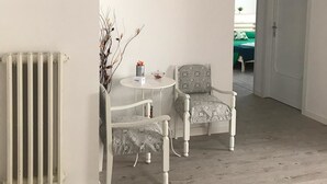 Ein Zimmer mit Heizkörper, zwei gemusterte Stühle, einem kleinen Tisch mit Schüssel und Tasse sowie einer Wand-Klimaanlage.