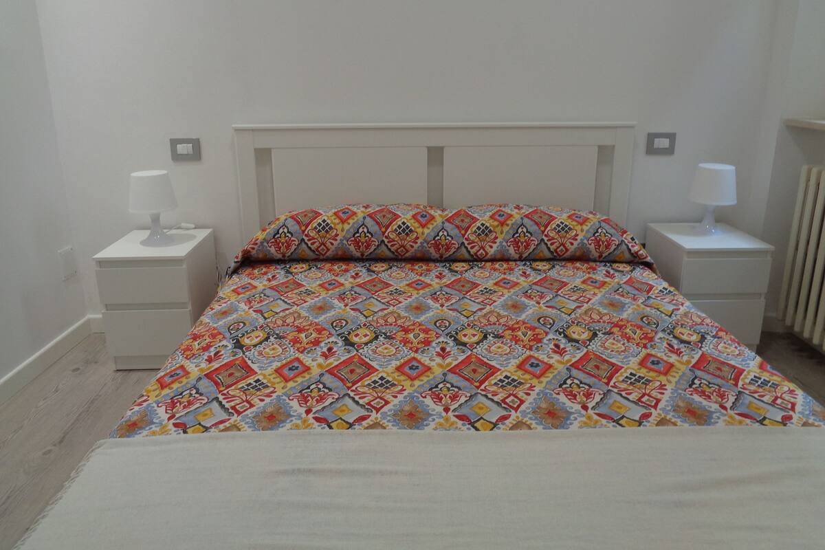 Une chambre à coucher avec un lit, deux tables de chevet et une petite table d’appoint.