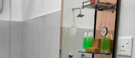 Un baño con un lavamanos blanco, un espejo con marco de madera y un estante de vidrio sobre el lavamanos.
