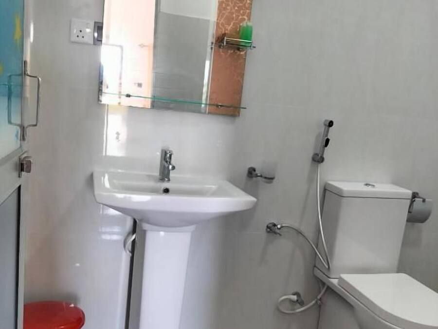 A bathroom with a white sink, a toilet, and a mirror.