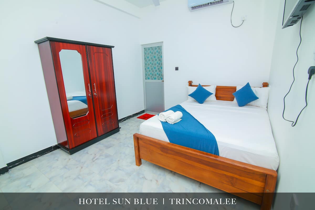 A hotel room with a bed, a wardrobe, and a bathroom.