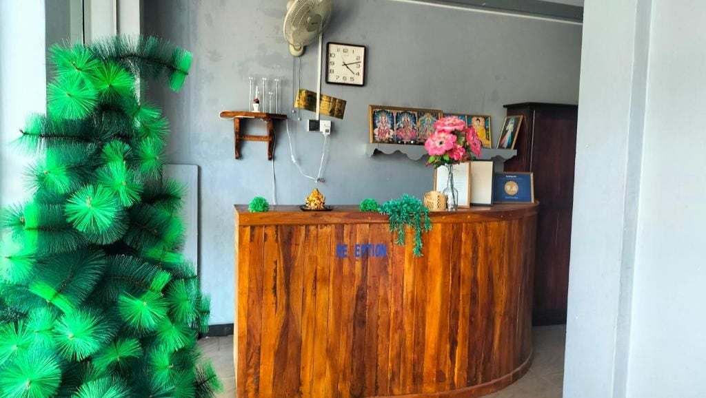 A reception desk with a clock, framed pictures, and a fan.