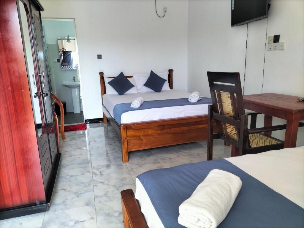A hotel room with a bed, a desk, a chair, a TV, and a bathroom visible in the background.