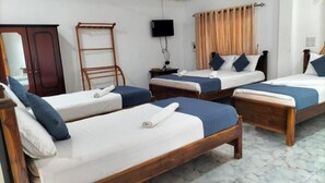 A hotel room with four single beds, a wooden wardrobe, a television, and a window with curtains. - Hotel Sun Blue (Trincomalee)