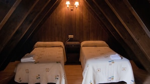 A small, cozy attic bedroom with two single beds, a nightstand, and a wall-mounted light fixture. - Hotel Eth Saueth (Naut Aran)
