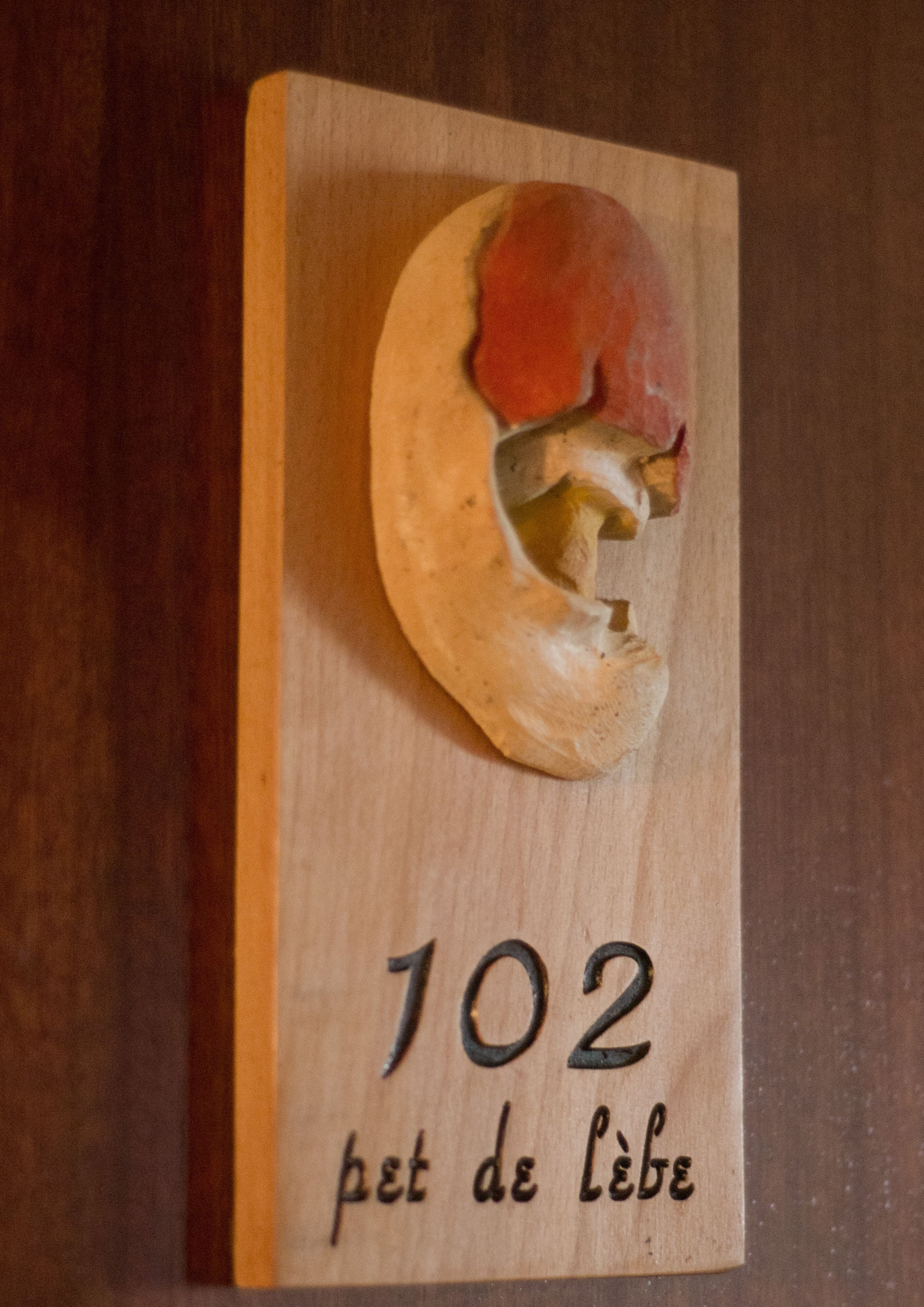 A wooden plaque with a carved figure and the number 102.