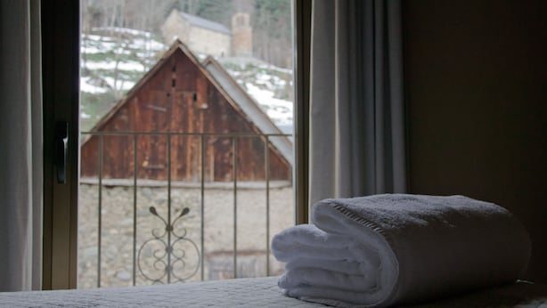 A window with a view of a wooden barn and a metal fence. A folded white towel is placed on a surface near the window. - Hotel Eth Saueth (Naut Aran)