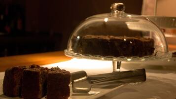 A dessert display with a cake under a glass dome and a knife beside it.