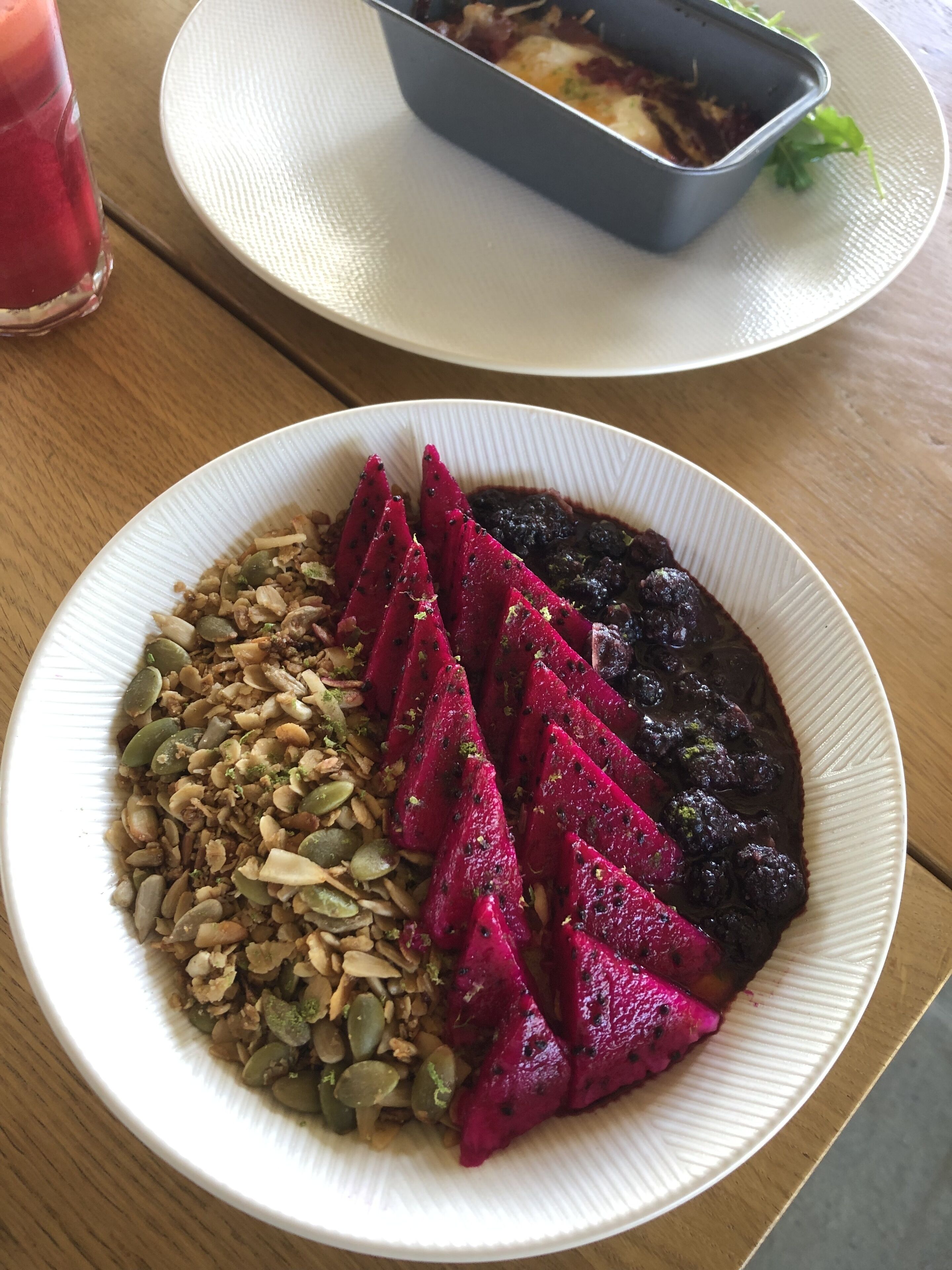 Ein Teller mit Salat, eine Schüssel Suppe und ein Glas Getränk auf einer Holztischplatte.