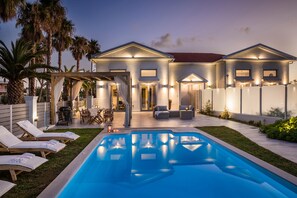 A modern house with a swimming pool, outdoor seating, and palm trees. - Lighthouse Villas Kefalonia (Kefalonia)