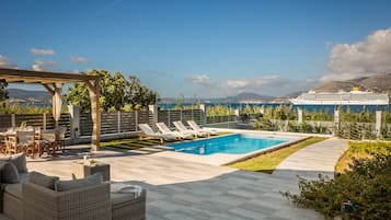 Relax by the pool, surrounded by a lush lawn and a pergola, with a dining area perfect for intimate meals.