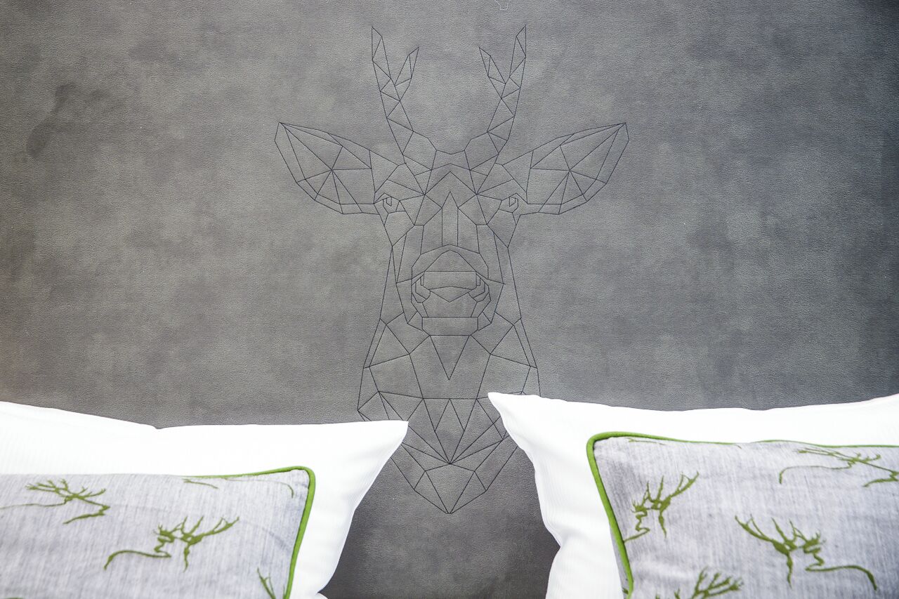 A geometric deer head design on a textured grey wall.