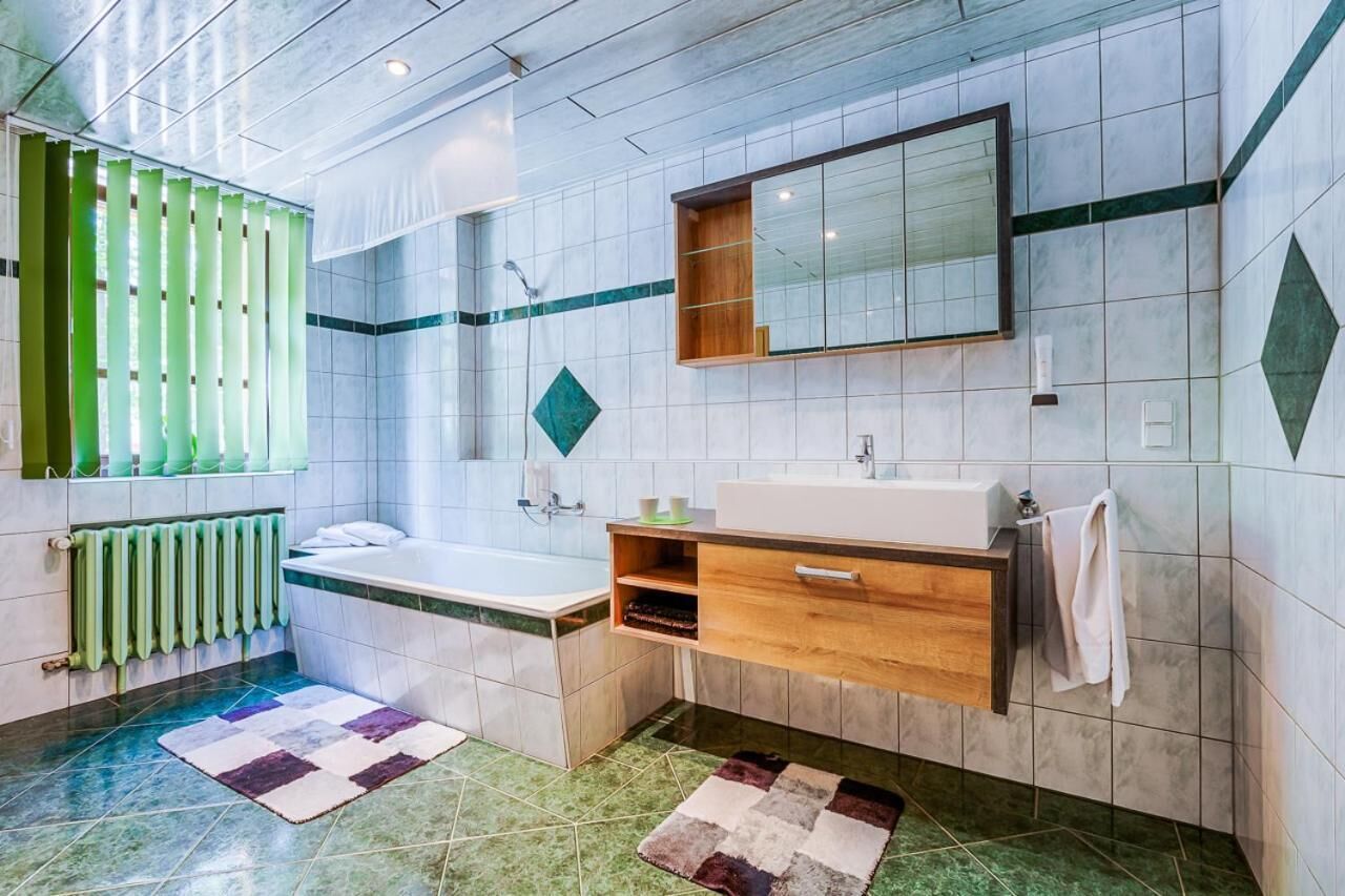 Et moderne badeværelse med badekar, et trækommode, et spejl og en radiator.