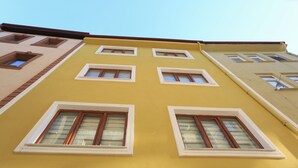 A multi-story building with a yellow facade and multiple windows. - Yildiz Pansiyon (Amasra)