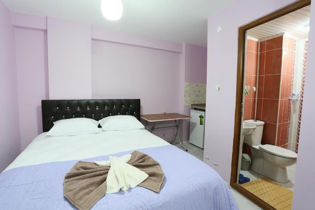 Un dormitorio con cama, escritorio y baño visible a través de una puerta abierta.