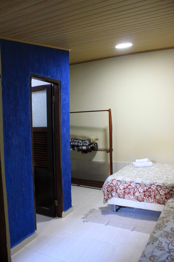 A bedroom with a bed, a wardrobe, and a door leading to another room. - Pousada do Sol (Alto Paraíso de Goiás)