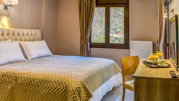A hotel room with a bed, a desk with breakfast items, a window with curtains, and a wall-mounted lamp.