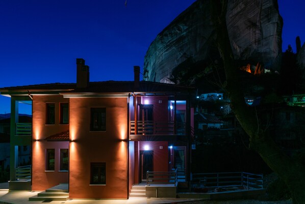 A multi-story building with a prominent rock formation in the background. - Elia Deluxe Accommodation (Kalabaka)
