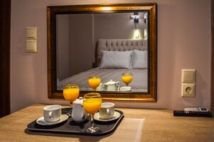 A hotel room with a large mirror reflecting a bed, a tray with breakfast items, and a remote control on the table.