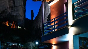 Un edificio moderno con un balcón y una gran formación rocosa al fondo.