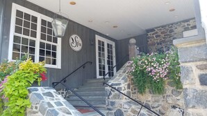 A spa entrance with a stone staircase, a sign reading "The Spa," and a flower bed with pink flowers. - The Inn at Montchanin Village, a Historic Hotel of America (Wilmington)