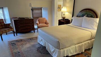 Ein Schlafzimmer mit einem großen Bett, einem Schminktisch, einem Sessel und einer Lampe.