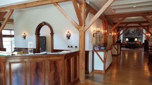 A spacious lobby with wooden beams, a reception desk, and a stone fireplace. - The Inn at Montchanin Village, a Historic Hotel of America (Wilmington)