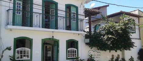A two-story building with green-framed windows and a balcony.