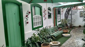 Un cortile con una panchina verde, piante in vaso e una piccola scalinata.