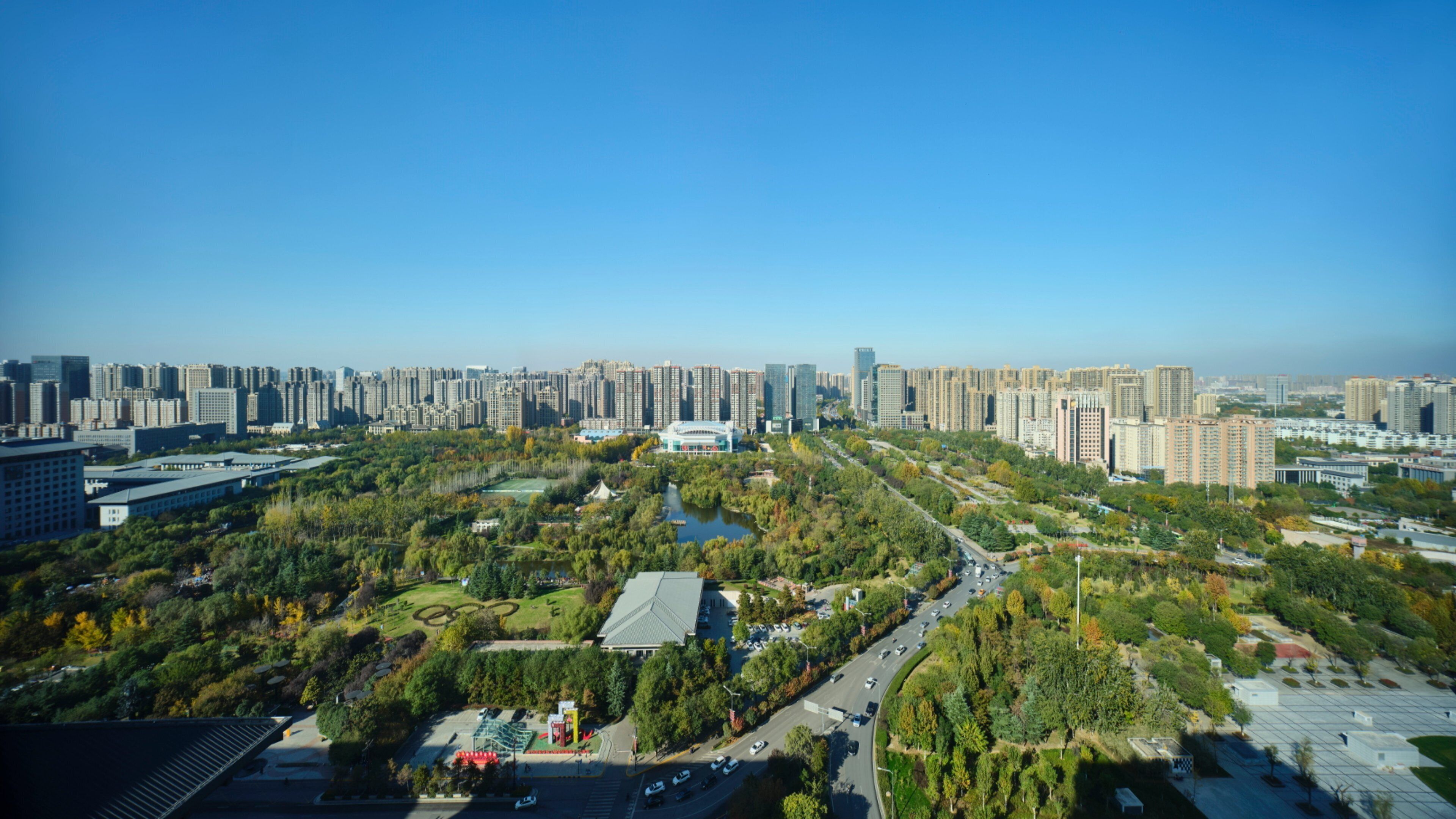 A high-rise urban area with dense residential buildings, a central park with a lake, and a large stadium.