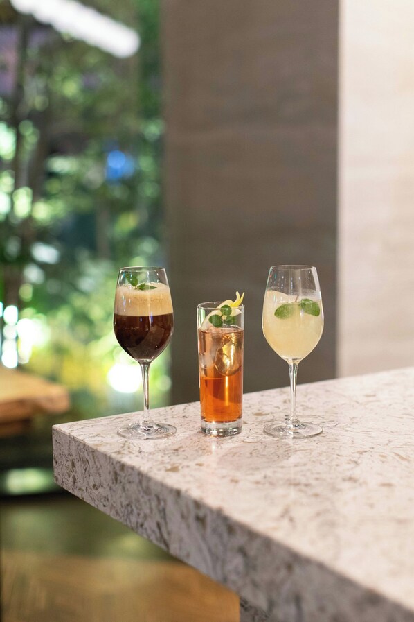Three glasses of beverages on a marble countertop with a blurred green background. - Courtyard by Marriott Osaka Honmachi (Osaka)