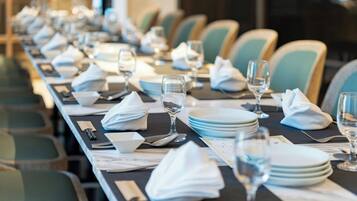 Una larga mesa de comedor dispuesta con platos, vasos y servilletas, rodeada de sillas.