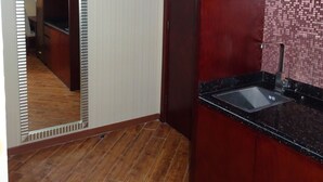 Una cocina con armarios de madera, encimera negra y salpicadero de azulejos.