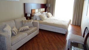 Una habitación de hotel con una cama, un sofá, una lámpara y un cuadro en la pared.