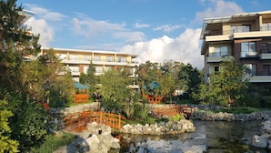 A courtyard with a pond, wooden bridge, and surrounding greenery. - Apartment on Batumskaya 16-9 ap. 22 (Batumi)