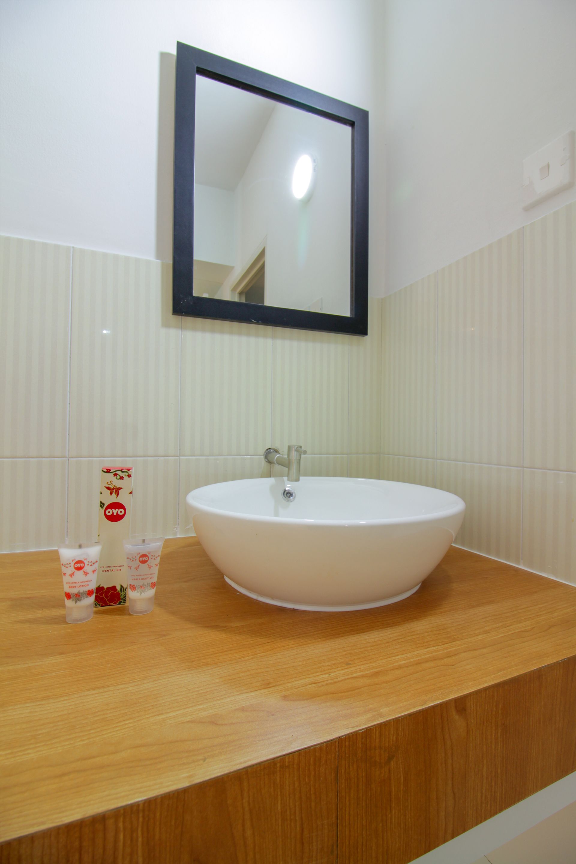 A bathroom with a white sink, a wooden countertop, and a mirror above the sink.