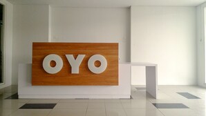A reception area with a large wooden panel displaying the letters "OYO" in white. - OYO Flagship 1260 Sentraland Karawang (Karawang)