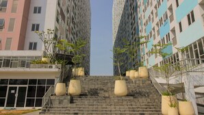 A modern building with a staircase leading to the entrance, surrounded by large planters with young trees. - OYO Flagship 1260 Sentraland Karawang (Karawang)