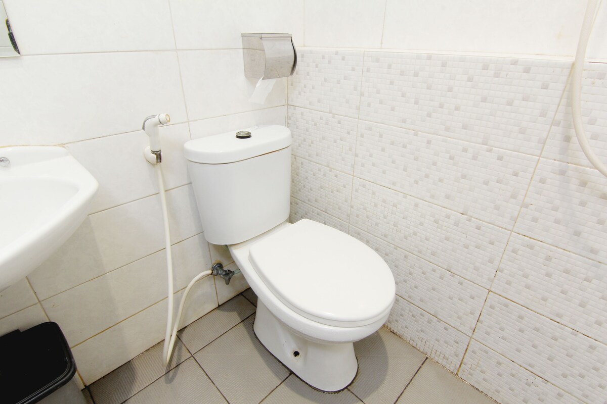 A bathroom with a toilet, sink, and tiled walls.