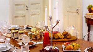 A dining table set with various food items, candles, and glassware. - Naca Suite (Catania)