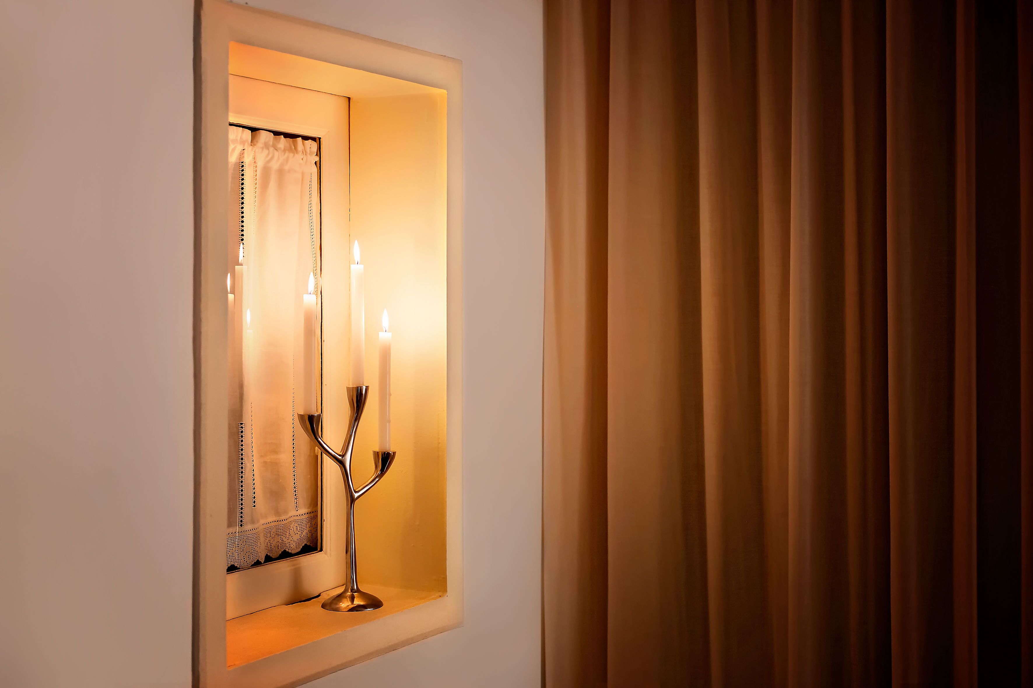 A window with a candelabra and candles, a curtain, and a wall with a window frame.