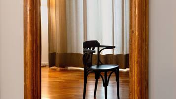 Un miroir avec un cadre en bois qui reflète une pièce contenant une chaise et des rideaux.