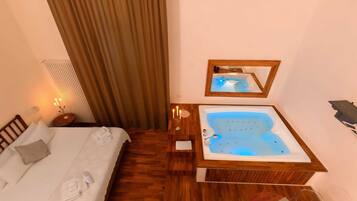 A hotel room with a bed, a wooden vanity with a bathtub, a mirror, and a nightstand with a lamp.